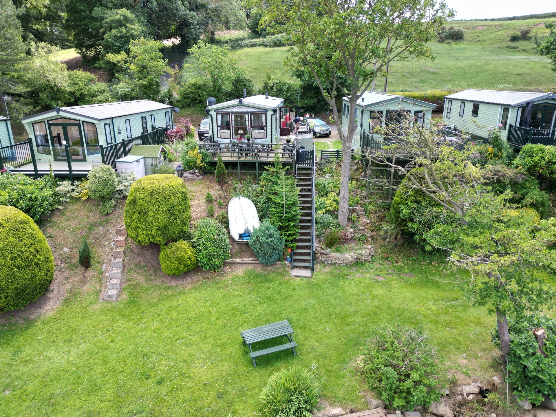 Green caravans on a hillside, with a grassy area and picnic table.