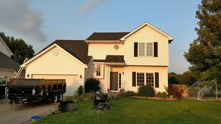 A white house with a dumpster in front of it