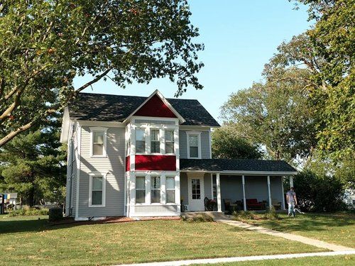 A white house with a red trim and a black roof