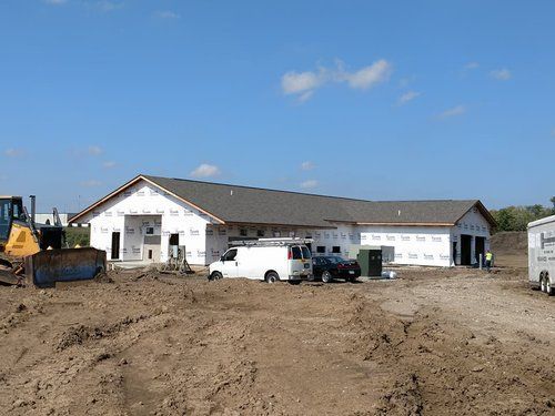 A bulldozer is parked in front of a building under construction.