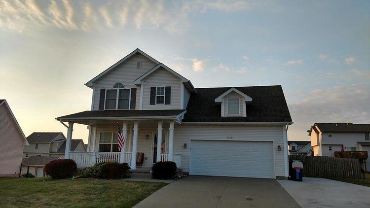 A white house with a black roof and a white garage door