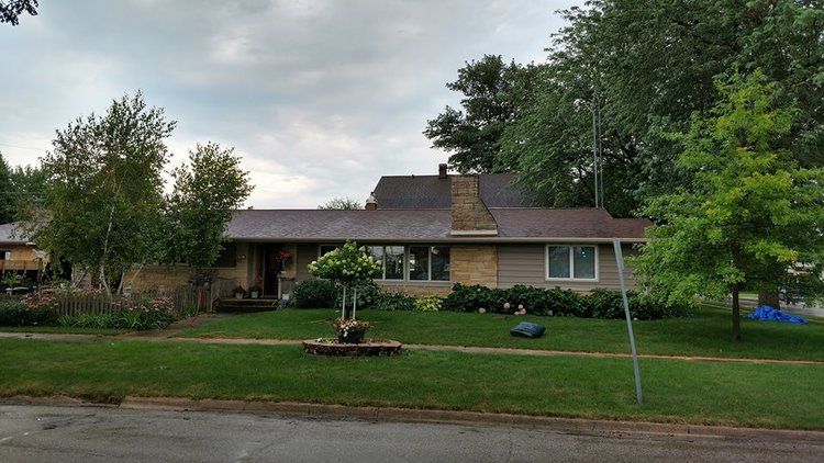 A house with a brown roof and a lot of trees in front of it