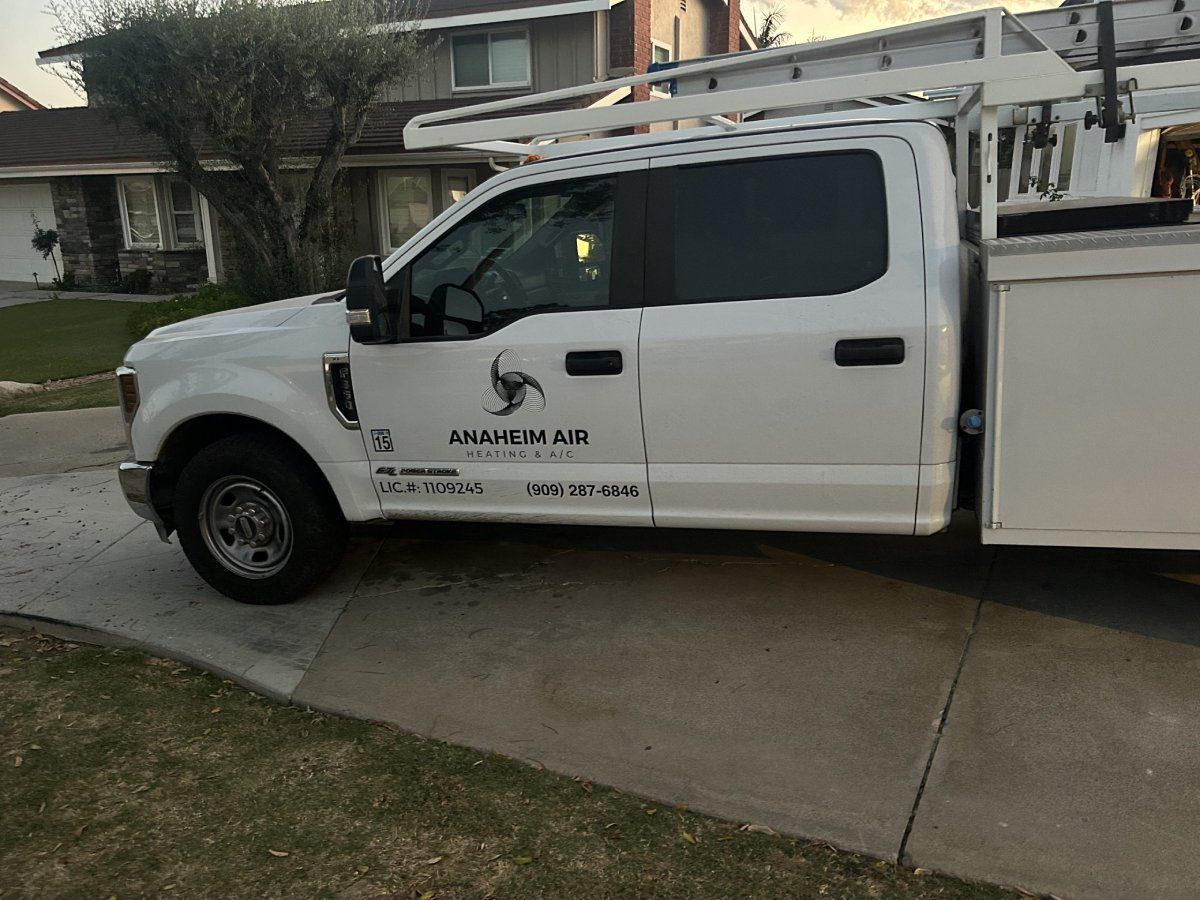 White work truck with logo parked on a driveway in front of a house.