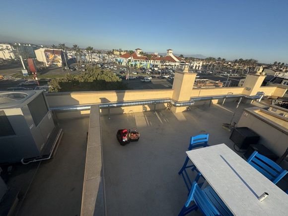 Rooftop with a lawnmower, blue furniture, and a city view on a sunny day.
