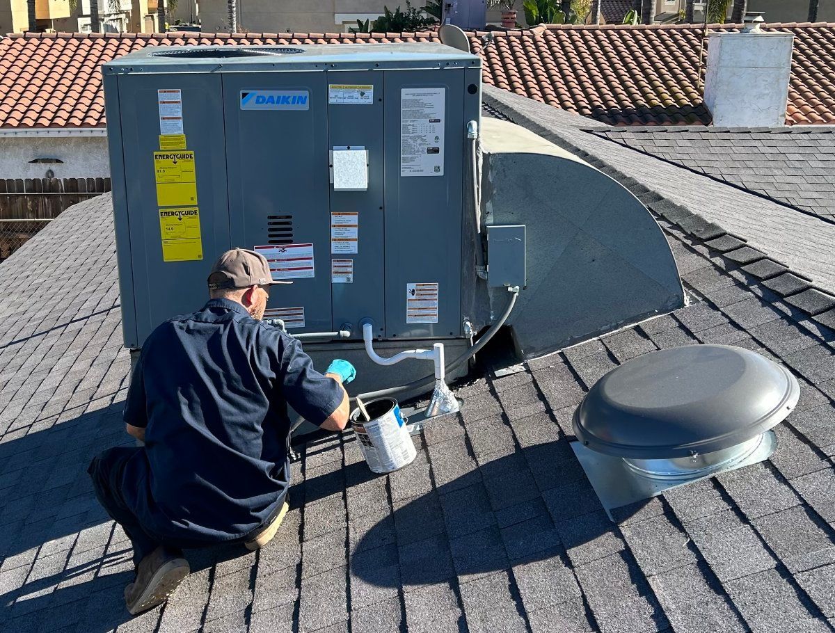 HVAC technician working on an air conditioning unit on a rooftop.