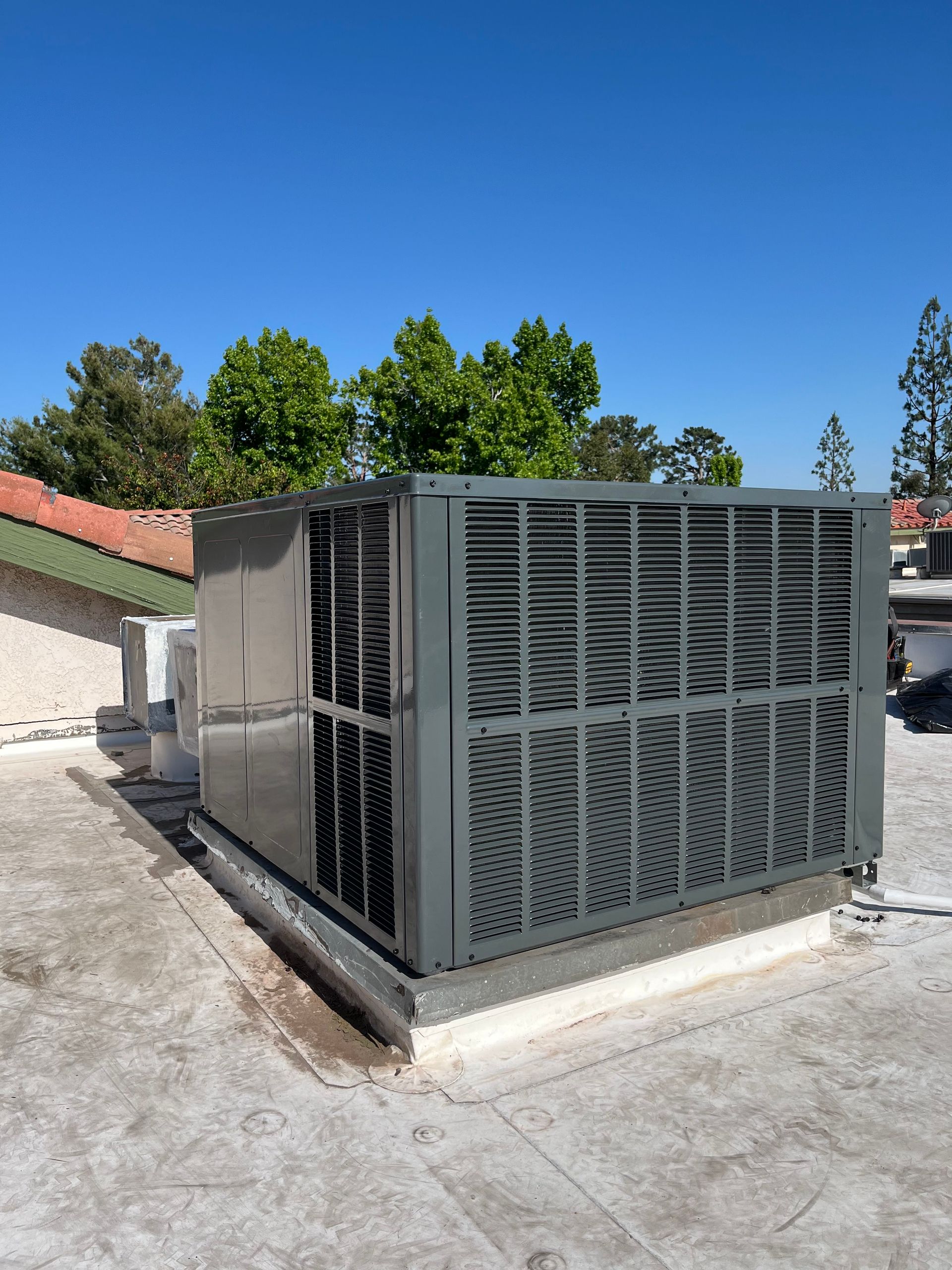 Large gray industrial HVAC unit on a rooftop under a clear blue sky.