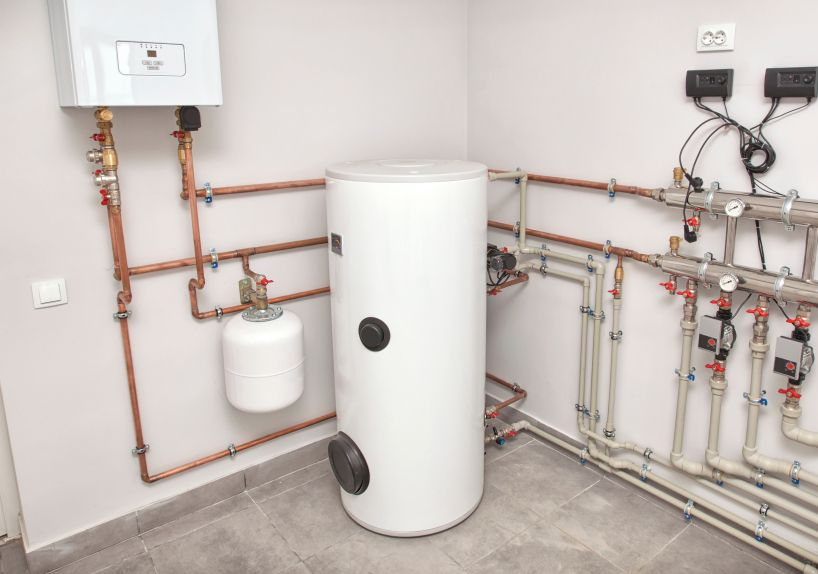Plumbing system in a utility room. Copper pipes and white water tank.