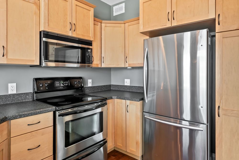 Kitchen with light wood cabinets, stainless steel appliances, and gray countertops.