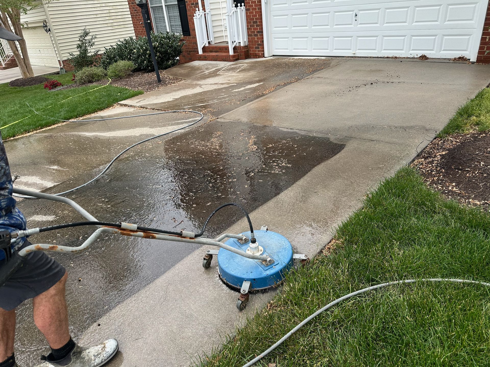 A man is cleaning a driveway with a pressure washer.