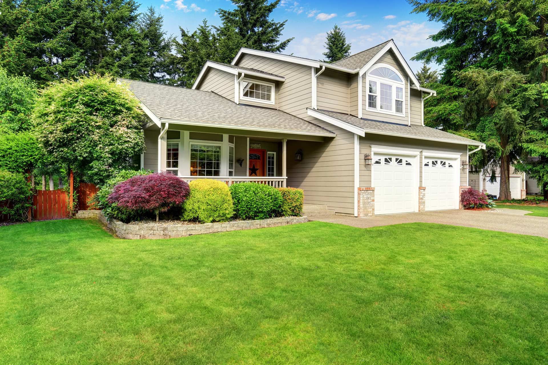 A large house with a lush green lawn and two garage doors