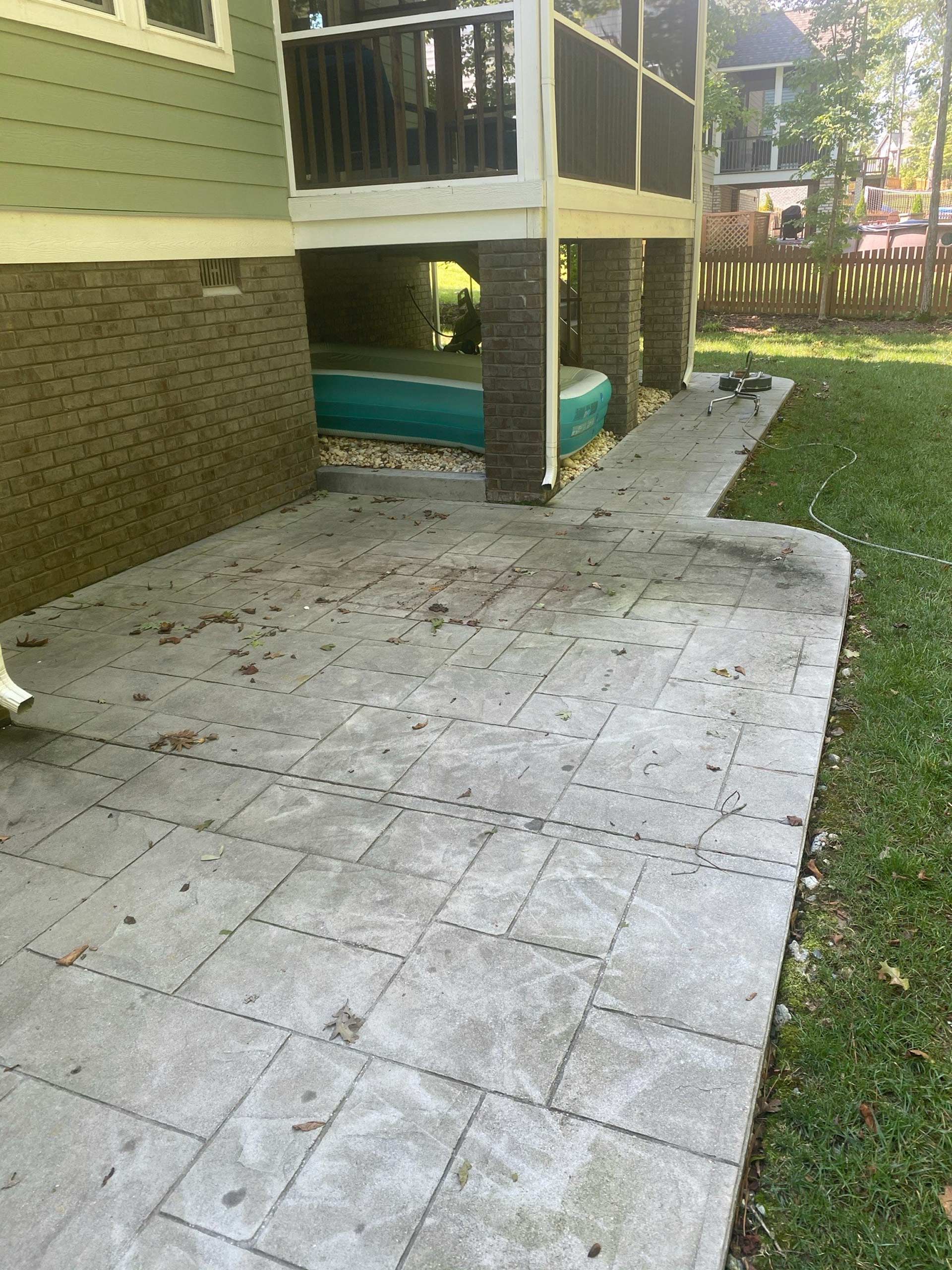 A concrete patio in front of a house with a screened in porch
