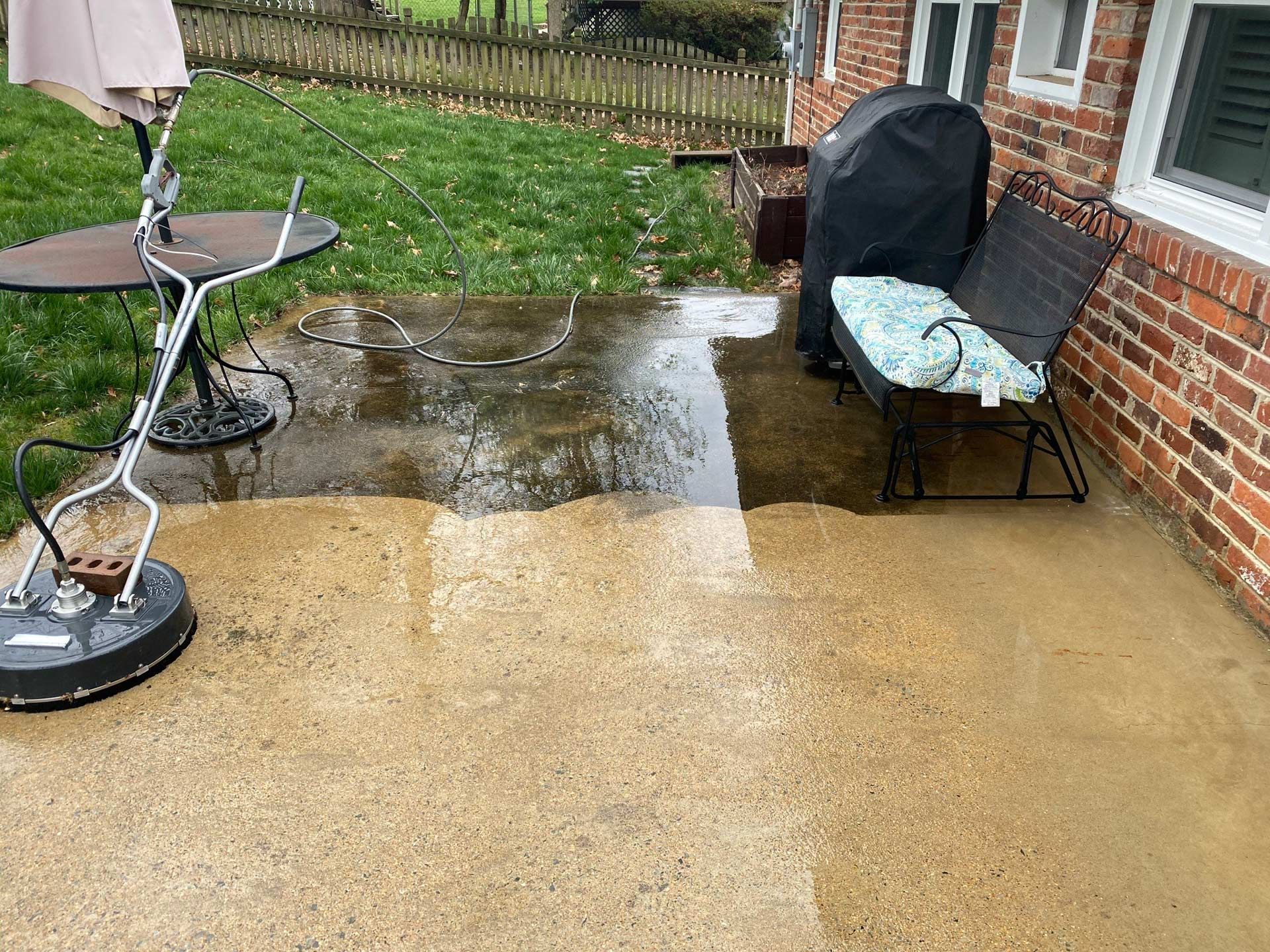 A patio with a table and umbrella in front of a brick house