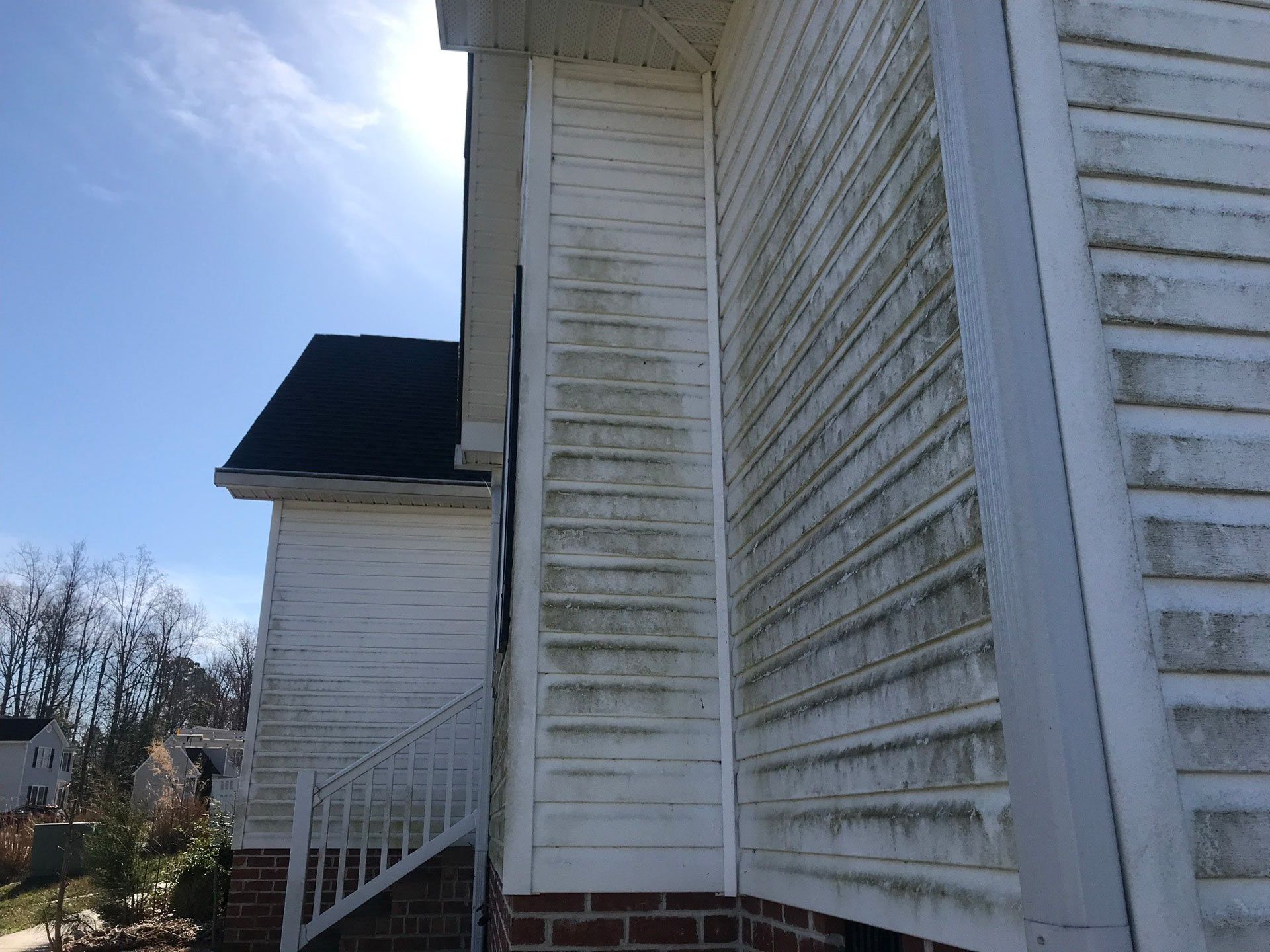 The side of a white house with a black roof and stairs