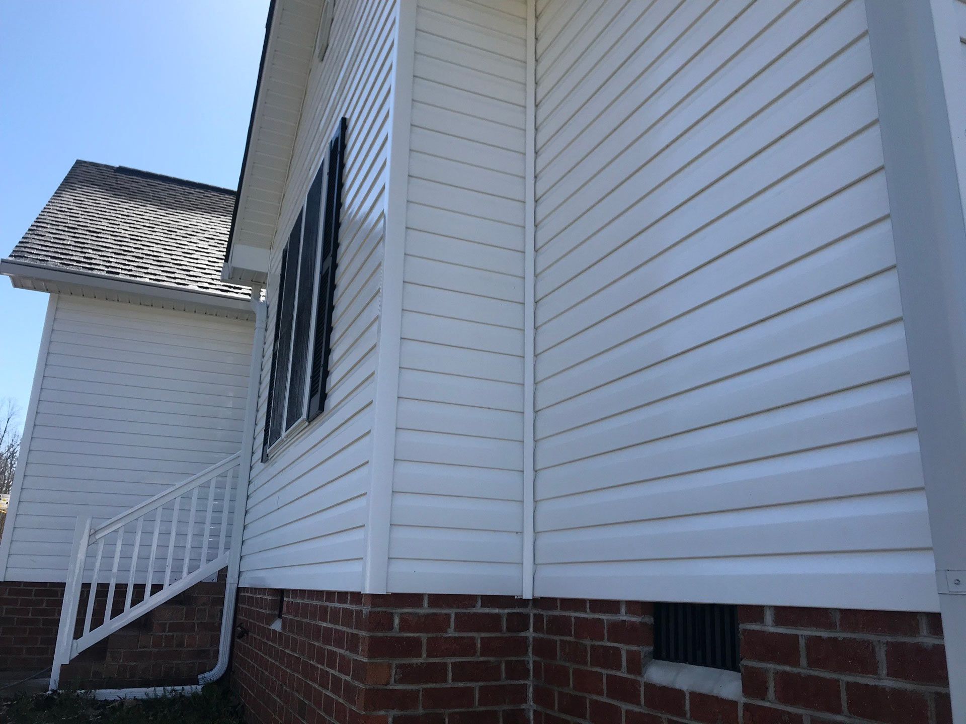 A white house with a brick foundation and white siding.