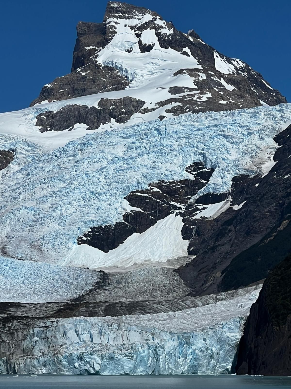 Una gran montaña cubierta de nieve con un glaciar en primer plano
