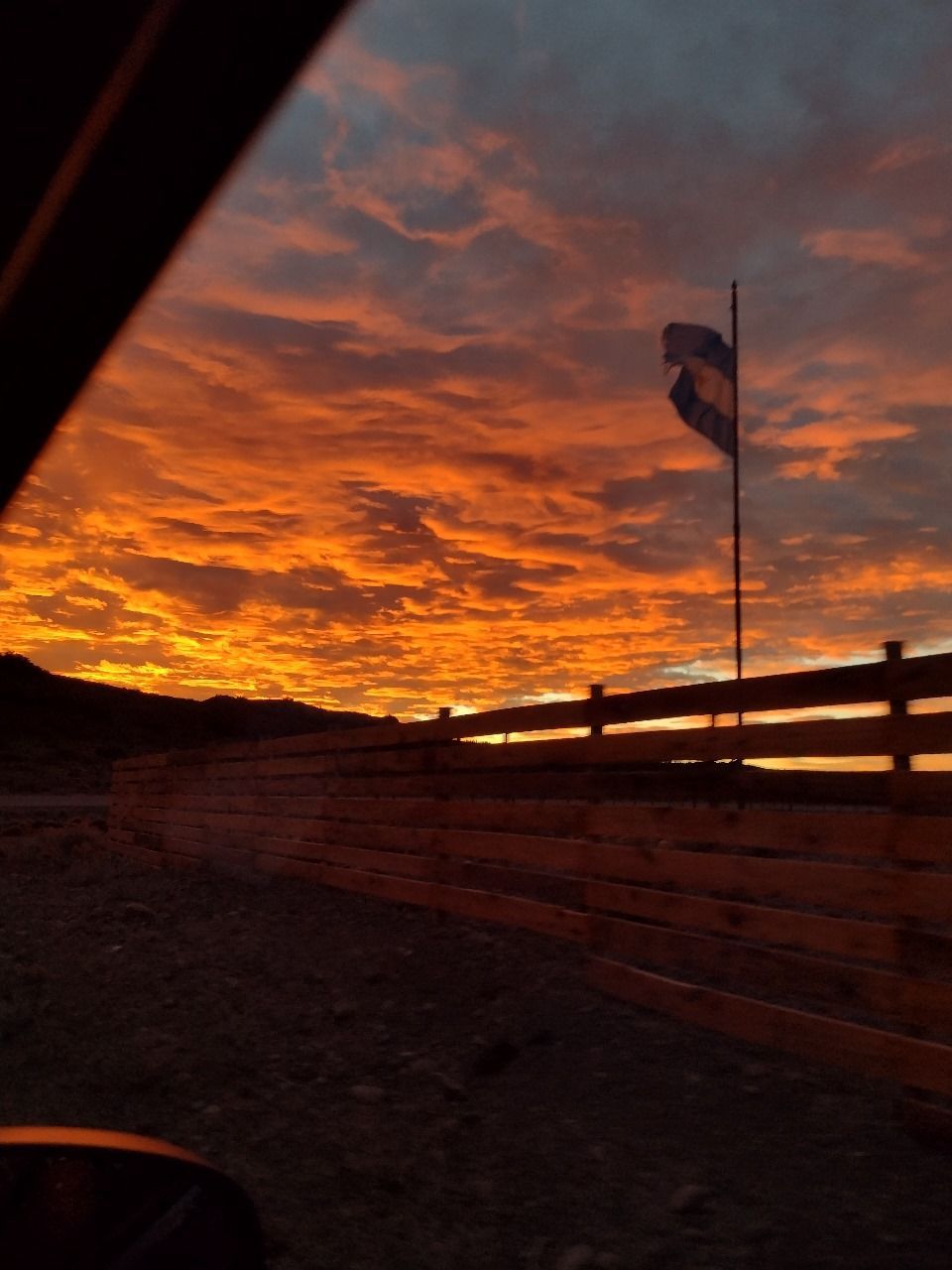 Una puesta de sol con una bandera en primer plano