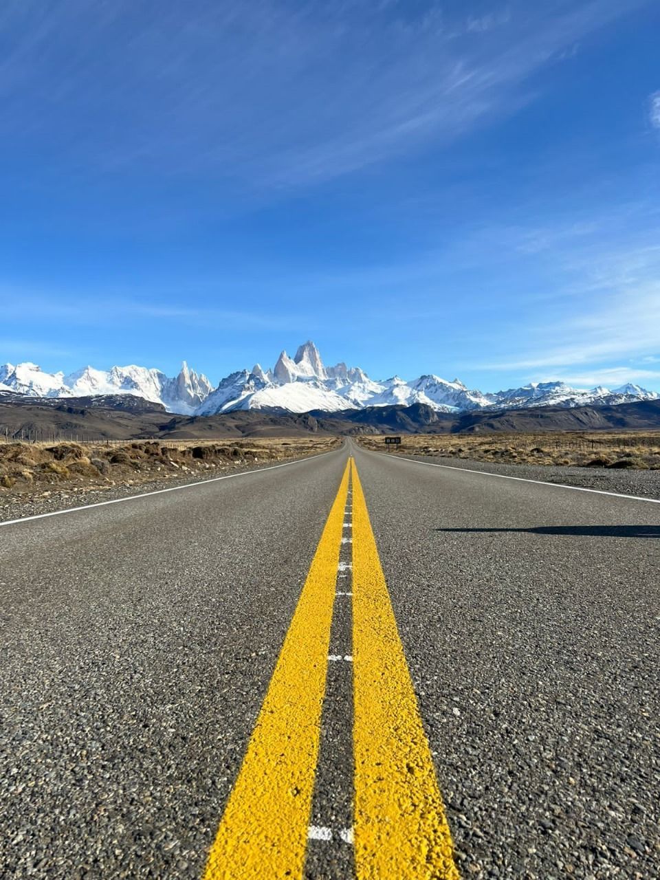 Una carretera con líneas amarillas y montañas al fondo