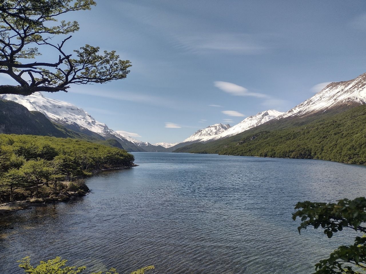 Un lago rodeado de montañas y árboles en un día soleado.