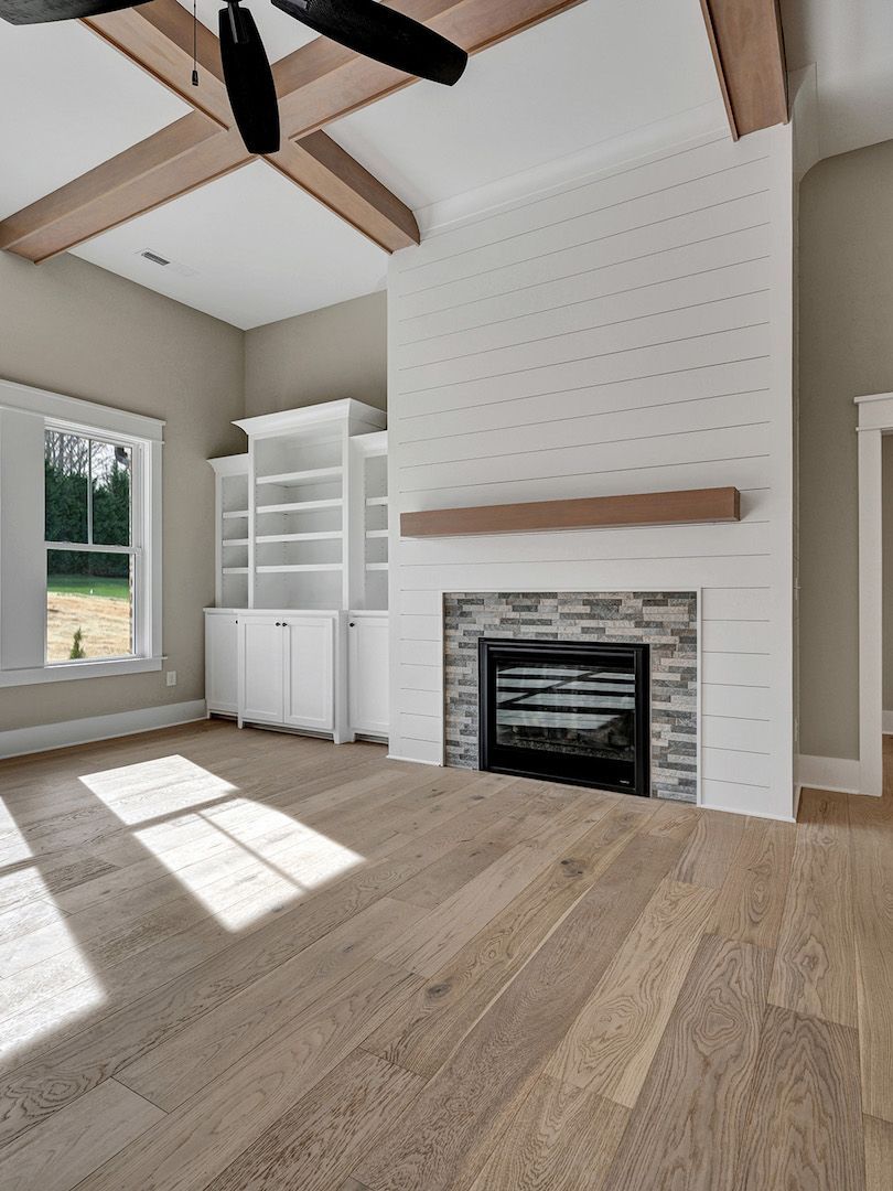 A living room with hardwood floors , a fireplace and a ceiling fan.