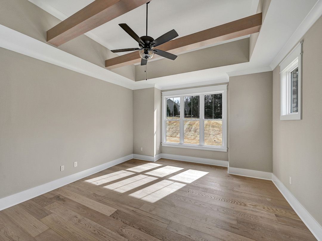 An empty room with hardwood floors and a ceiling fan.