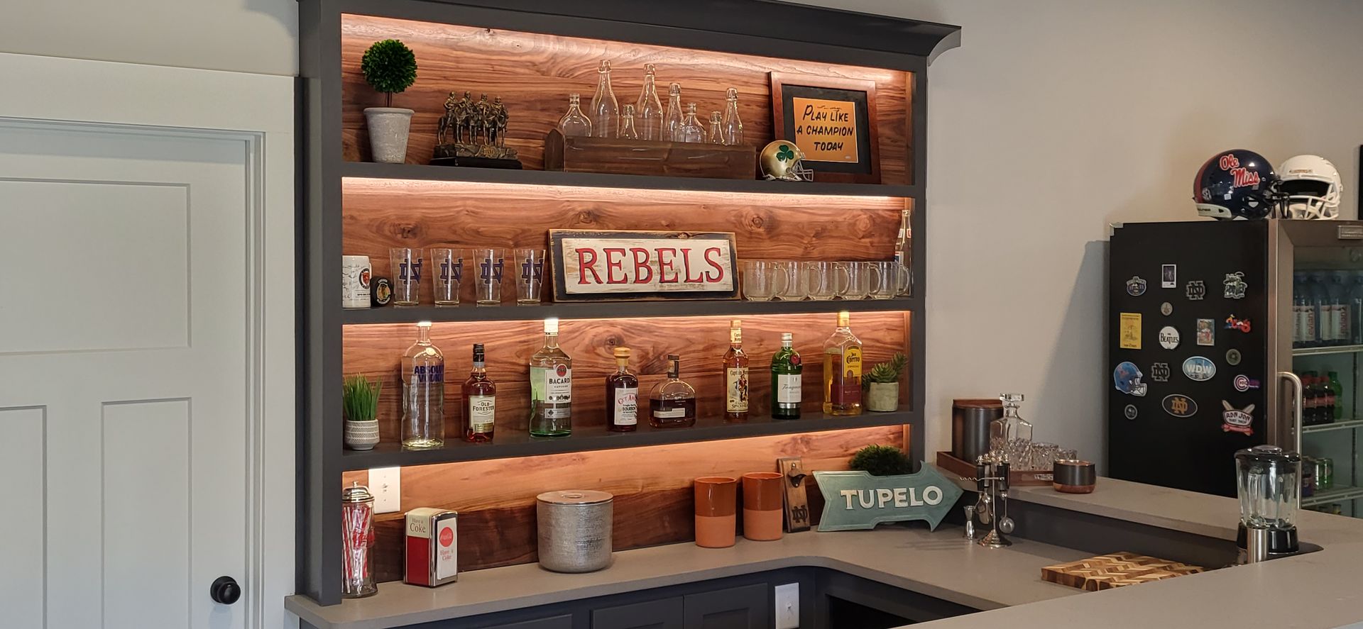 A bar with a lot of bottles and glasses on the shelves.