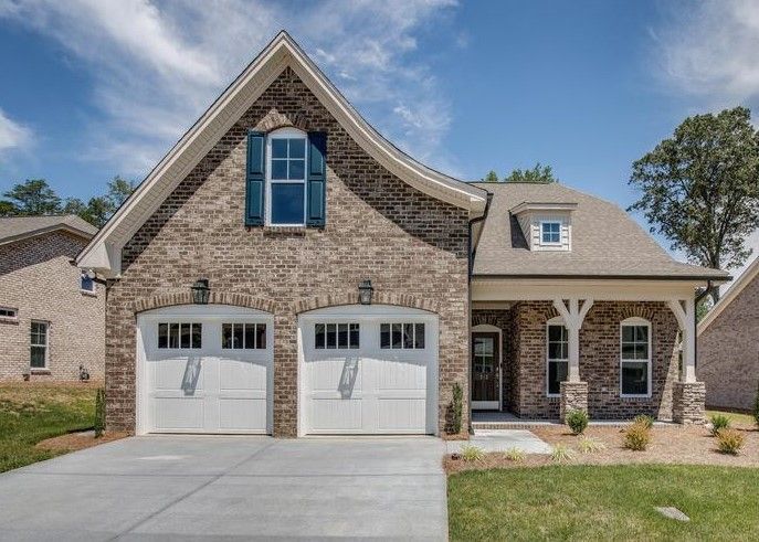 A brick house with two white garage doors and blue shutters.