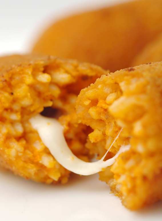 Un primo piano di una crocchetta di riso fritto rotta che rivela un ripieno filante di mozzarella fusa.
