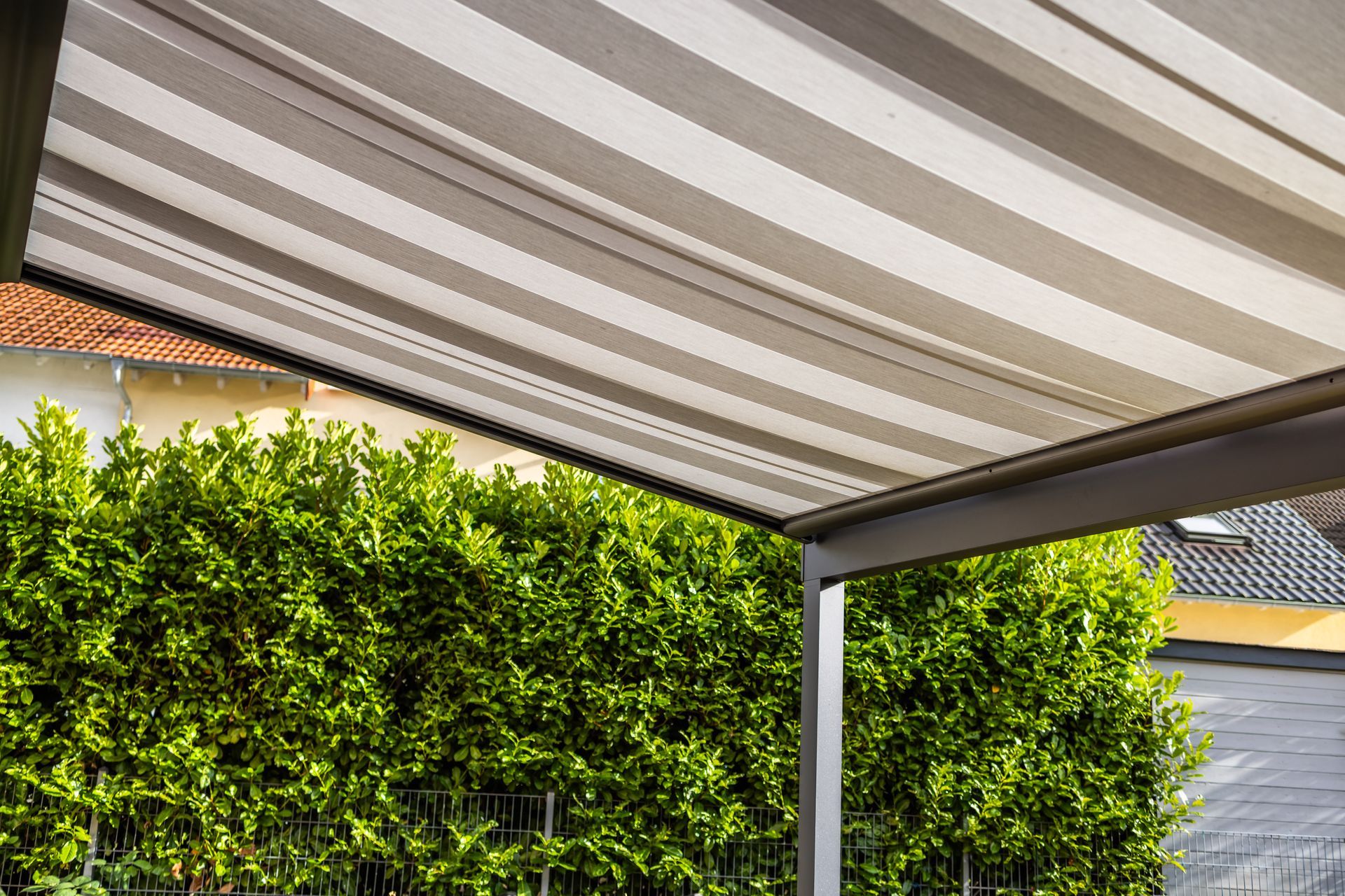 A custom awning with beige and white striped fabric in a residential home's backyard