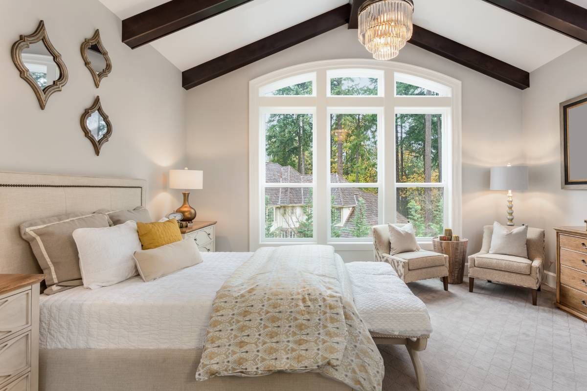 Modern bedroom with vaulted ceiling, bed, and seating area