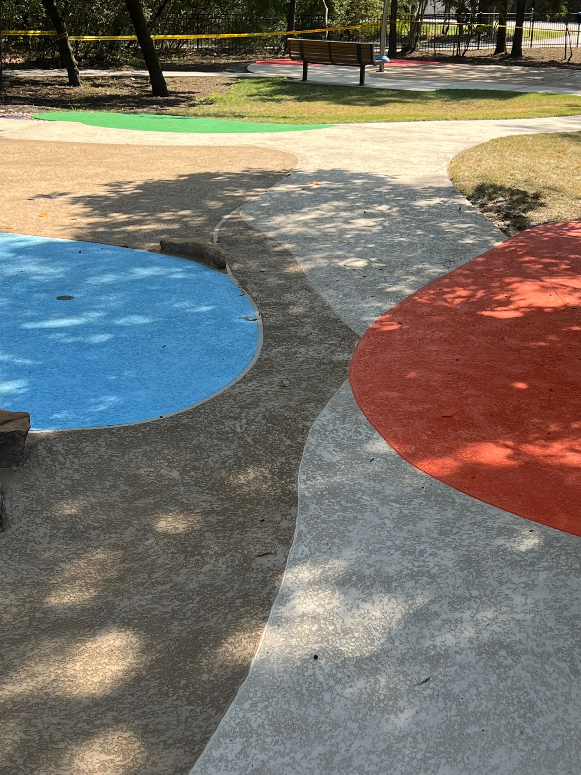 A playground with circles painted on the ground and trees in the background.