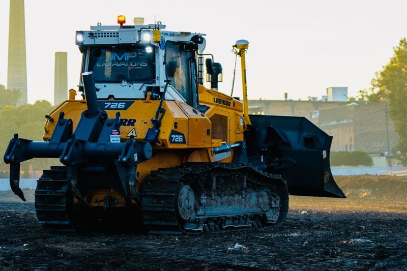 A bulldozer is driving through a dirt field.