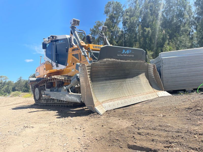 A bulldozer is sitting on top of a dirt field.