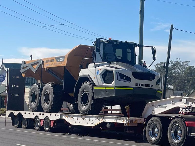 A dump truck is sitting on top of a trailer.