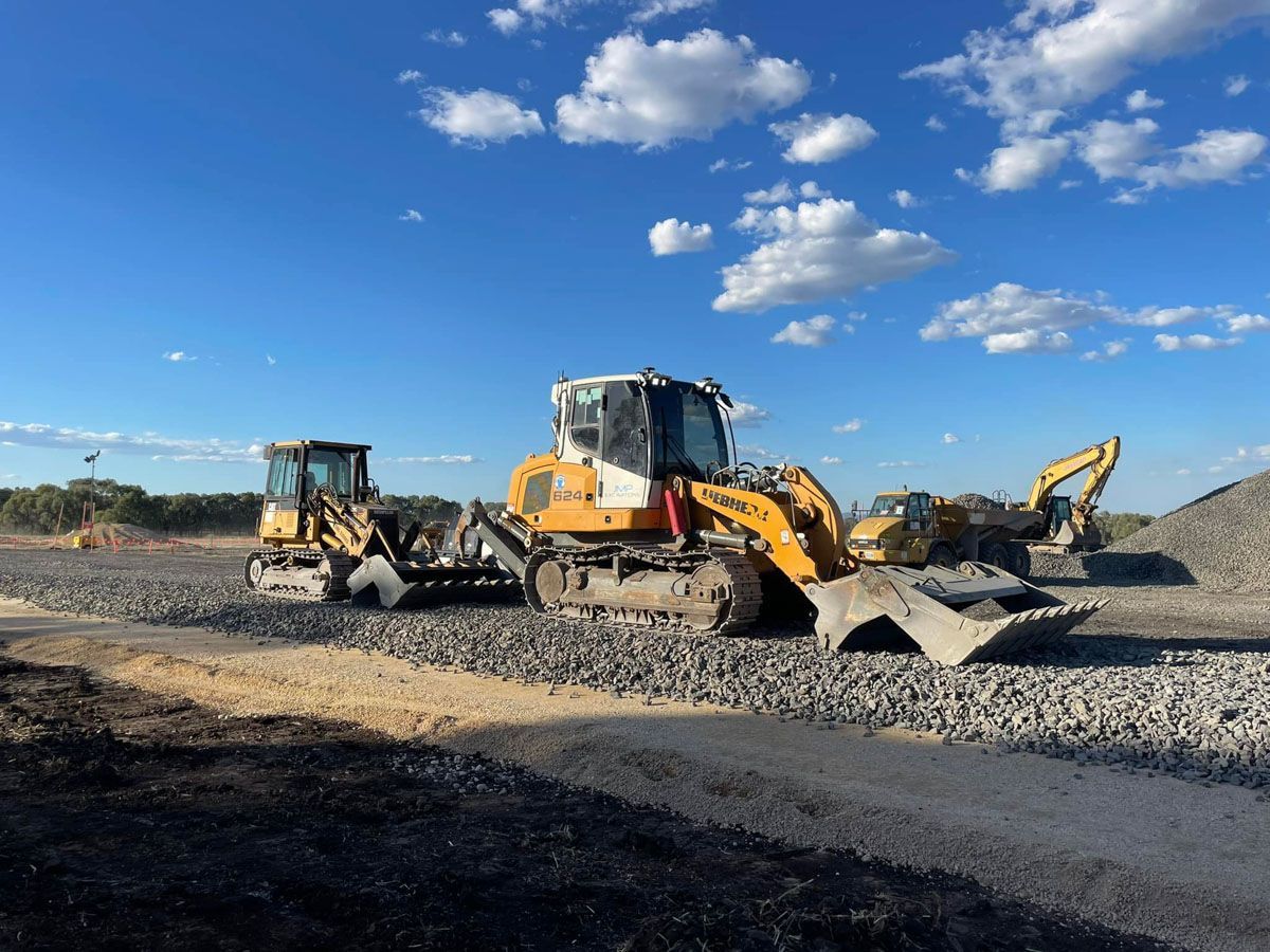 A group of construction vehicles are parked on a dirt road.