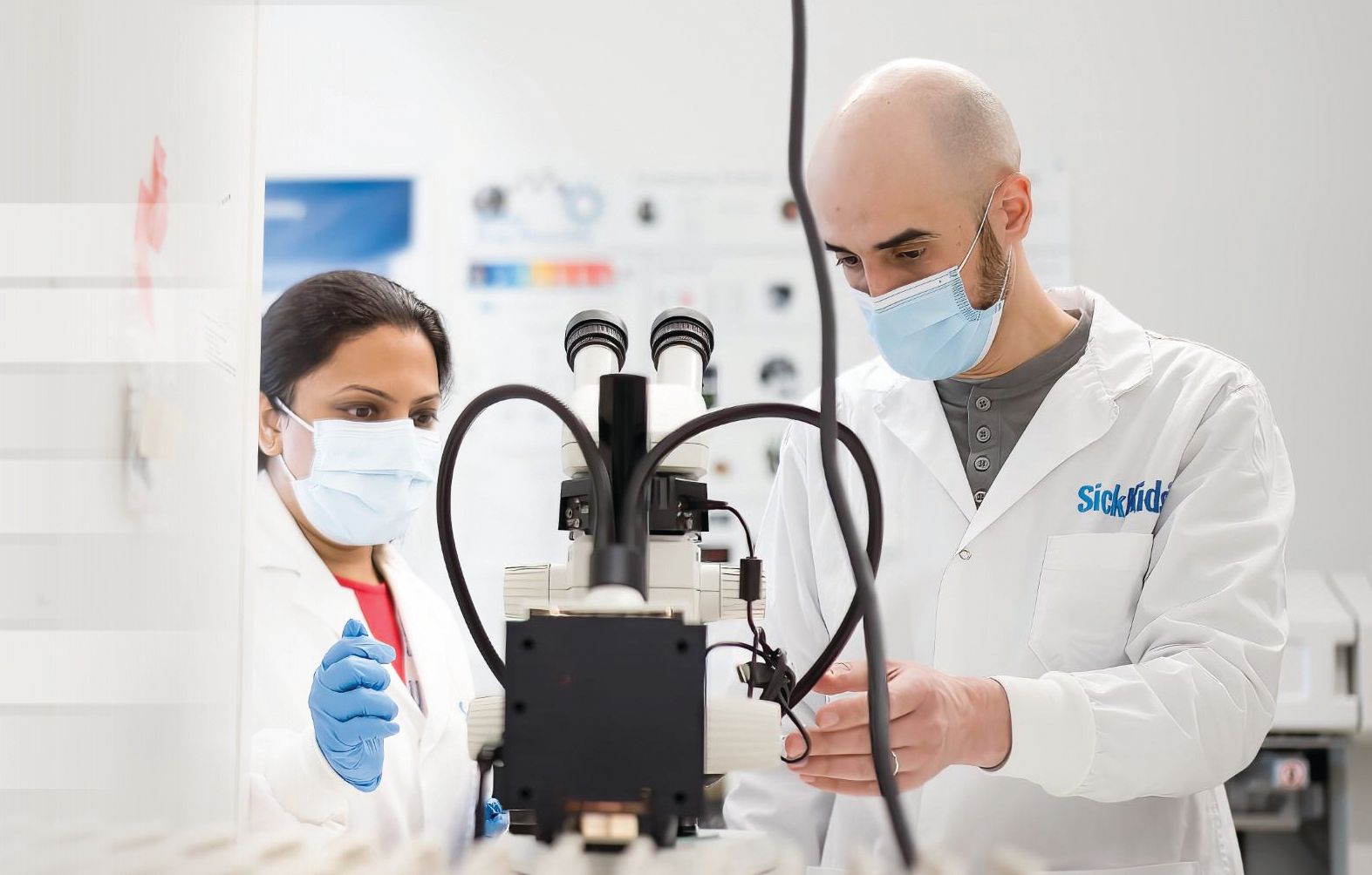 Two Sick Kids researchers working in lab on complex medical equipment.