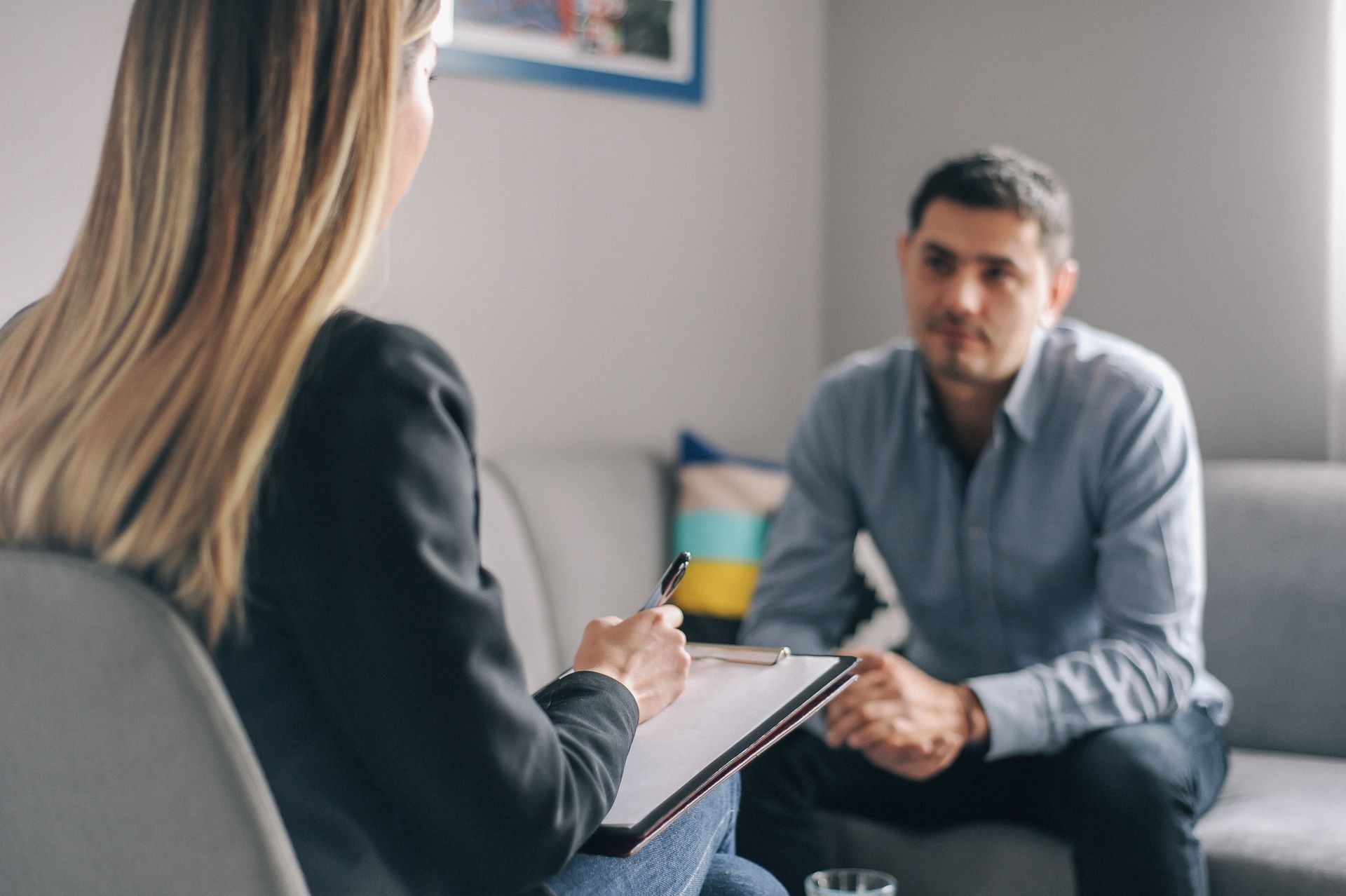 A woman is sitting on a couch talking to a man.