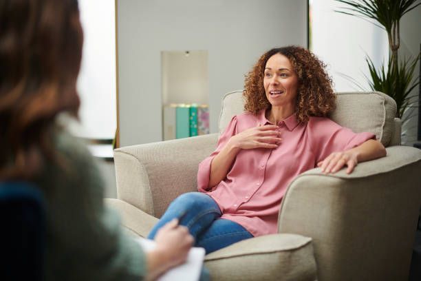 A woman is sitting in a chair talking to another woman.
