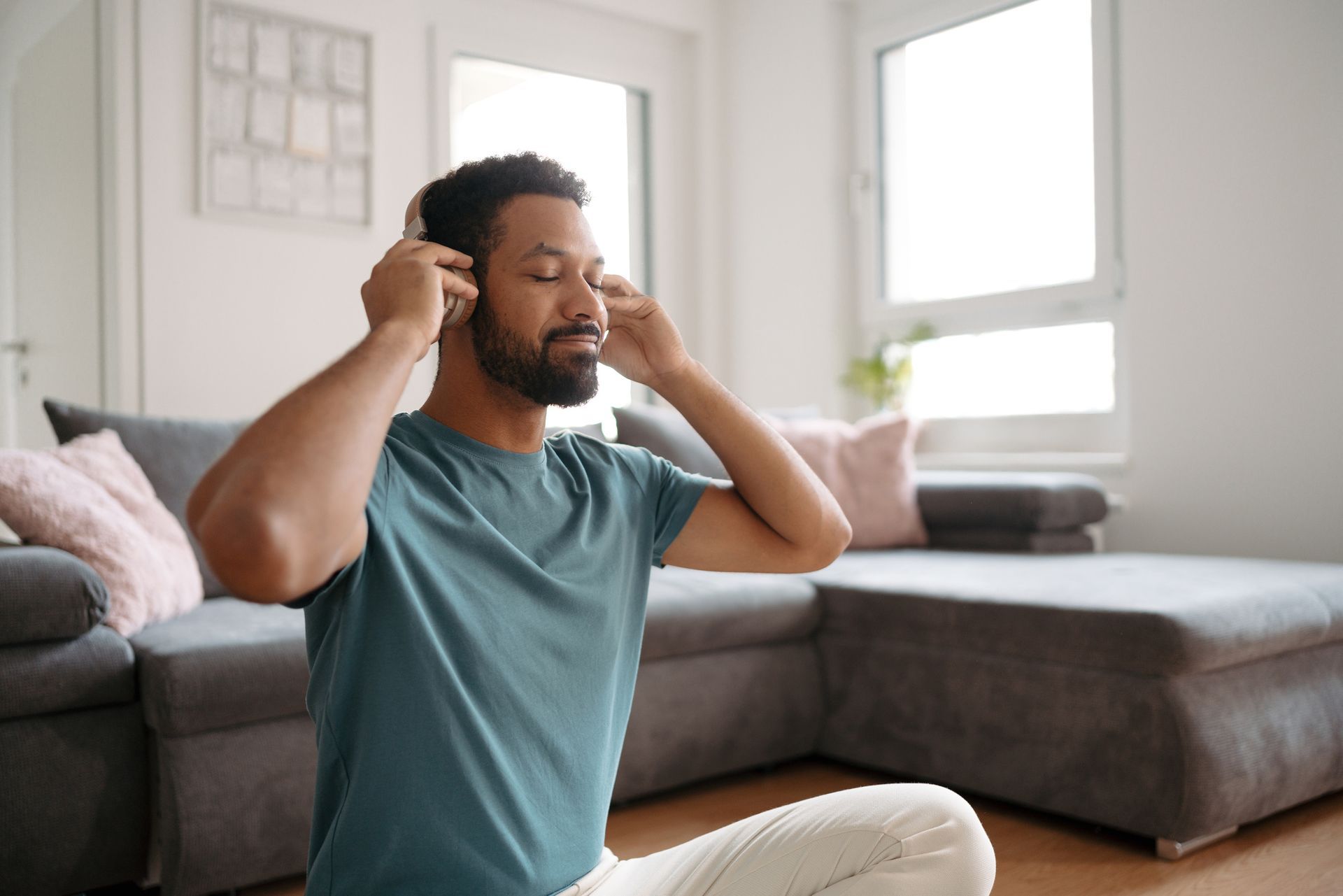 A man is sitting on the floor in a living room wearing headphones.