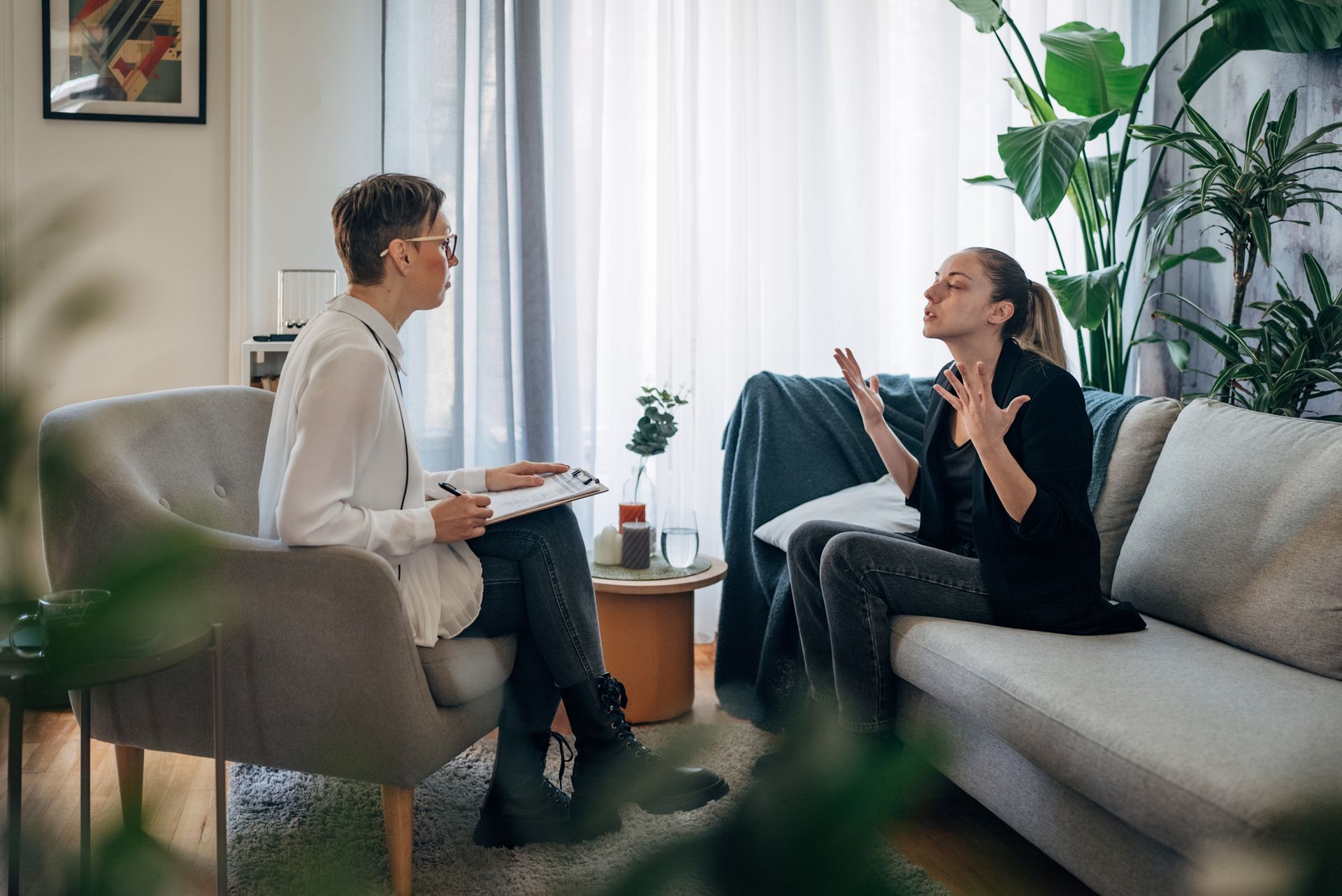 A woman is sitting on a couch talking to a doctor.