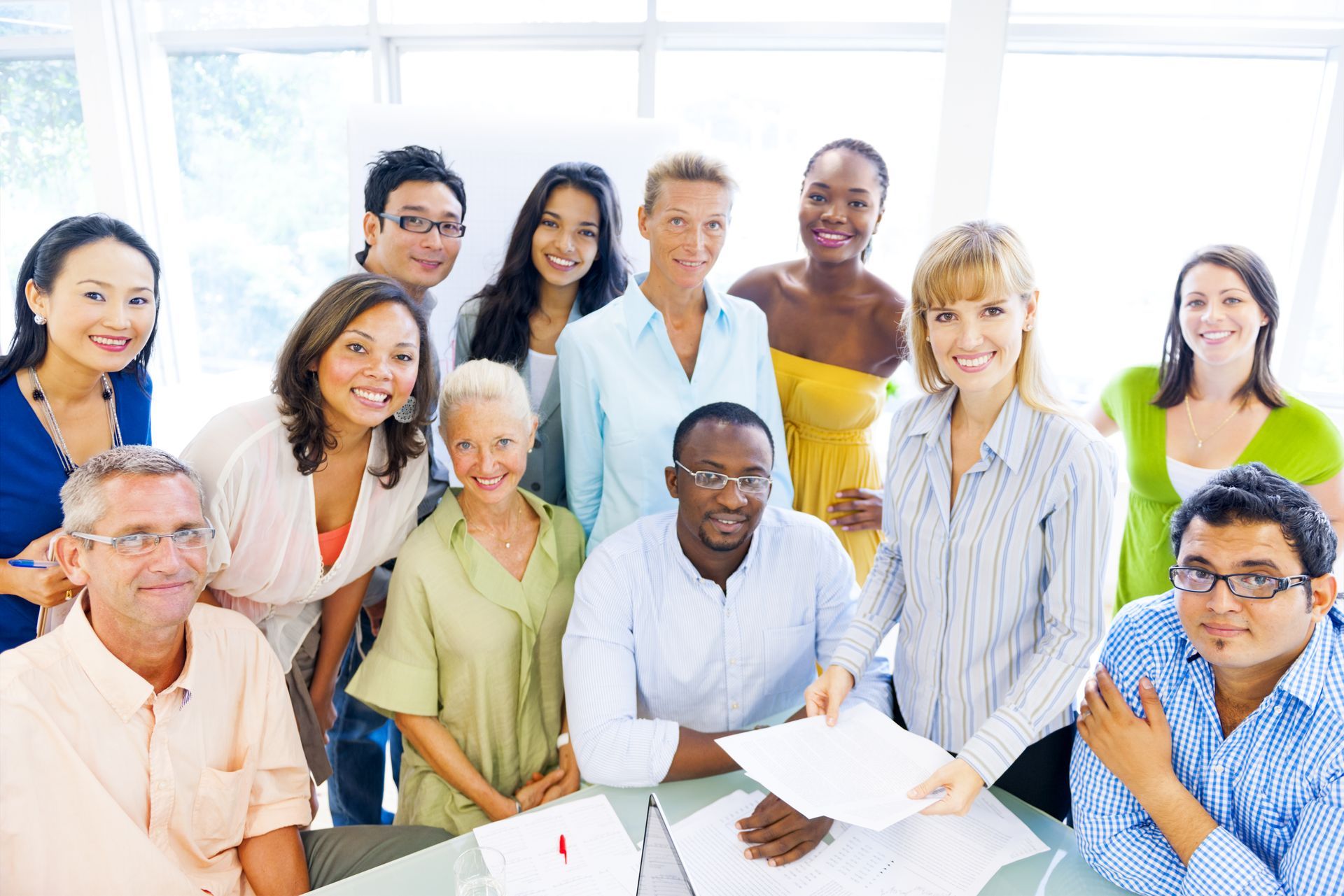 A group of people are posing for a picture while sitting around a table.