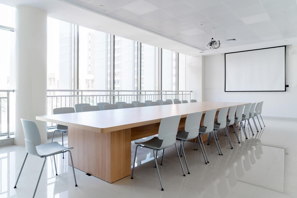 A conference room with a long table and chairs and a projector screen.