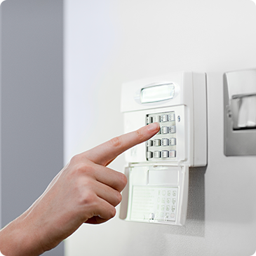 A person is pressing a button on a security system with their finger.