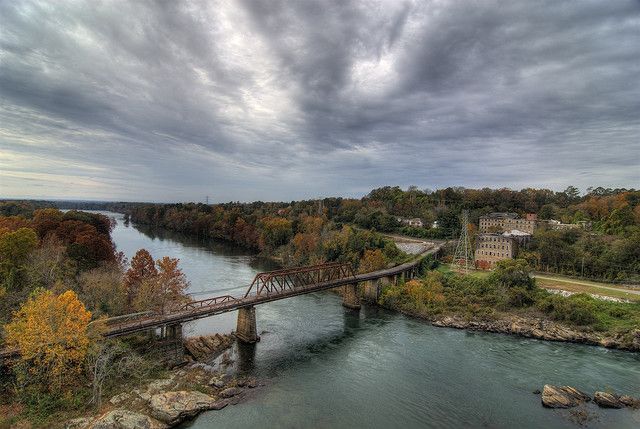 An aerial view of a bridge over a river surrounded by trees.