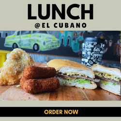 Almuerzo en El Cubano: Sándwich cubano, croquetas, pastel, taza de café, mesa de madera, mural de carro de fondo.