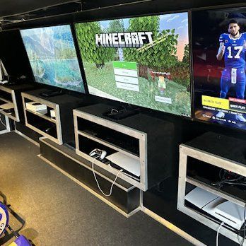 A video game room with three televisions playing minecraft.