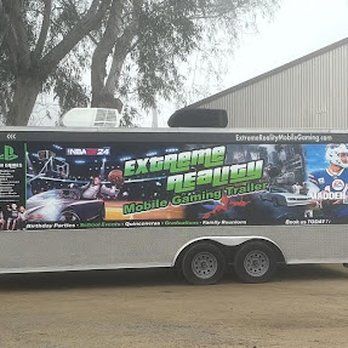 A trailer with a playstation logo on the side is parked in front of a building.