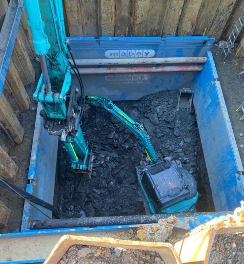 A blue crane is sitting in a hole in the ground.