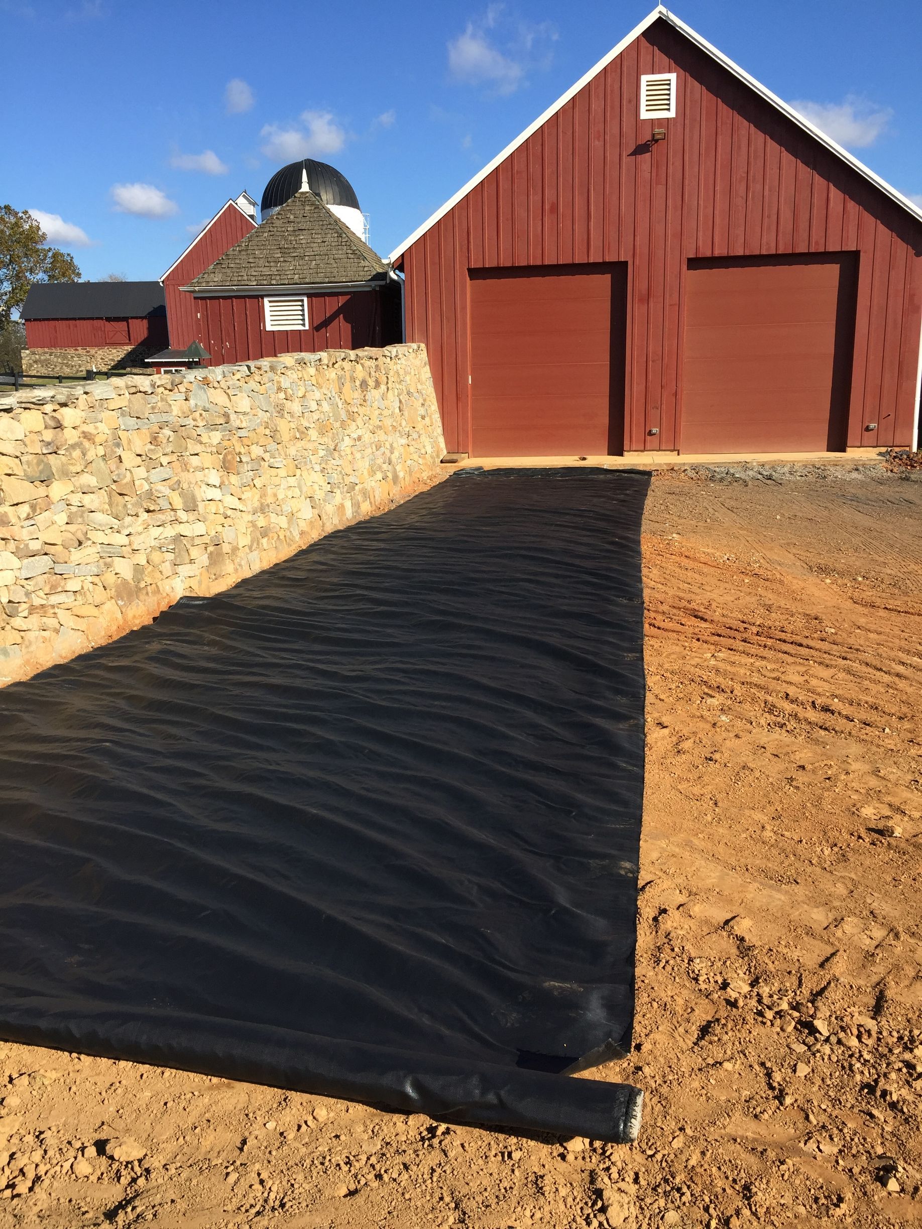 A red barn with a black tarp in front of it