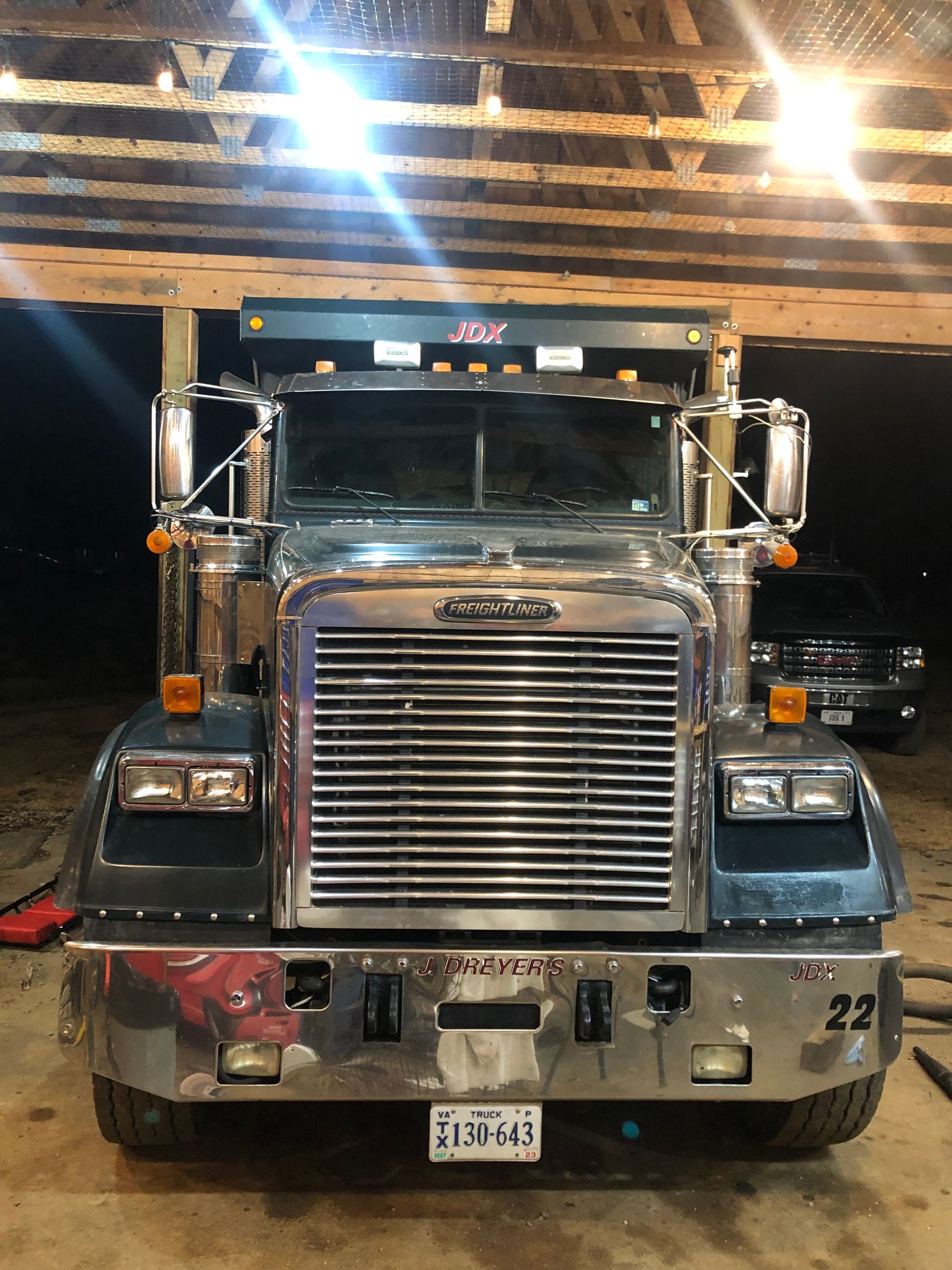 A semi truck is parked under a wooden roof in a garage.