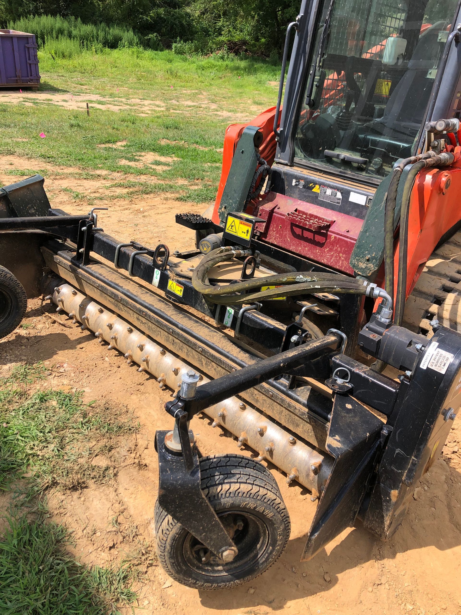 A red and black tractor is sitting on top of a dirt field.